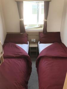 2 Betten in einem kleinen Zimmer mit Fenster in der Unterkunft Our Happy Place! in Weymouth