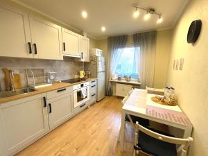 a kitchen with white cabinets and a table in it at Cozy Home Apartment Lielvardes, free parking, self check-in in Rīga