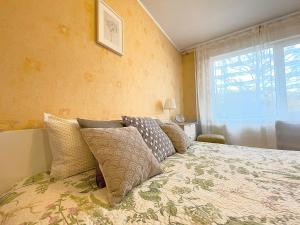 um quarto com uma cama com almofadas e uma janela em Cozy Home Apartment Lielvardes, free parking, self check-in em Riga