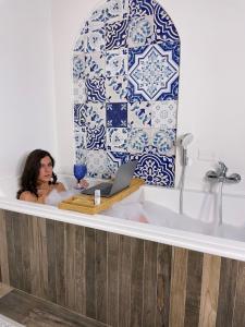 a woman taking a bath in a bath tub with a laptop at Relais Mareluna - Luxury Apartments in Salerno
