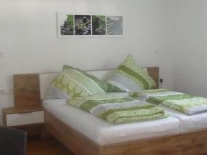 a bed with green and white pillows on it at Ferienwohnungen Baust im Mühlental in Eslohe