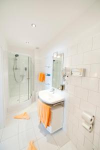 a white bathroom with a sink and a shower at Hotel Spöttel in Bad Nauheim