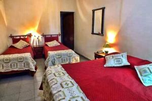two beds in a room with red sheets at Hotel inty raimi in Salta