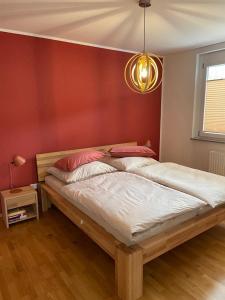 Ce lit se trouve dans une chambre dotée d'un mur rouge. dans l'établissement Ferienwohnung Lavendel, à Lahr/Schwarzwald