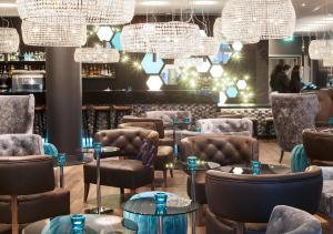 un restaurante con mesas, sillas y lámparas de araña en Motel One London-Tower Hill, en Londres