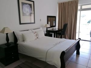 a bedroom with a large white bed and a desk at Sunset Boulevard Riverlodge in Paarl