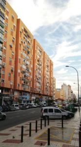 una calle de la ciudad con coches aparcados frente a edificios altos en Casa Princesa Huelin en Málaga