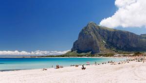 a group of people on a beach with a mountain in the background at Casa Vacanza Stella del Mare in San Vito lo Capo