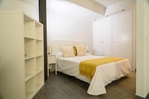 a white bedroom with a bed and shelves at Estudio Constitución by Renthas in Málaga