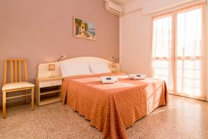 a bedroom with a bed and a chair and a window at Hotel Lydia in Cervia