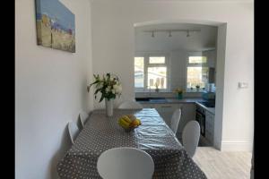 uma cozinha com uma mesa de jantar com cadeiras e um estofador de mesa em No43: Versatile 4BR coastal home with summer house em Cowes