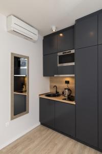 una cocina con armarios negros y fregadero en Apartments Urbis, en Dubrovnik