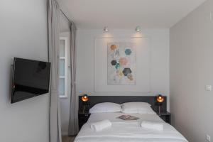 1 dormitorio con 1 cama blanca y TV de pantalla plana en Apartments Urbis, en Dubrovnik