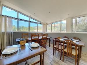 - une salle à manger avec des tables, des chaises et des fenêtres dans l'établissement A Guinguetta, à Venaco
