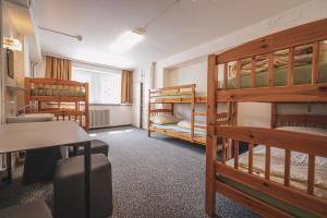 a room with three bunk beds and a desk at Arosa Mountain Lodge in Arosa