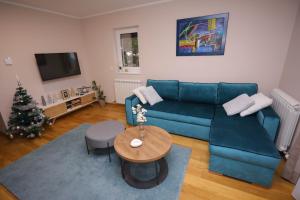 sala de estar con sofá azul y árbol de Navidad en Mipet apartmani, en Zlatibor