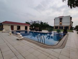 a swimming pool with two statues in front of a house at The Fern An Ecotel Hotel, Lonavala in Lonavala