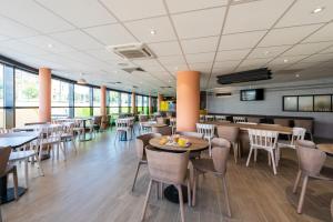 una sala da pranzo con tavoli, sedie e finestre di B&B HOTEL Nice Aéroport Arenas a Nizza