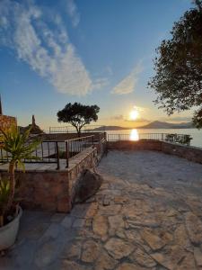 a sunset over the water with a stone walkway at Apartments Mitrovići Miločer in Sveti Stefan