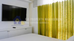 a bedroom with a yellow curtain and a tv at East Bay Residences @ Sucat Muntinglupa in Manila