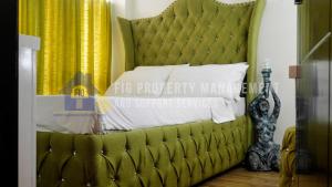 a bedroom with a green bed with a yellow curtain at East Bay Residences @ Sucat Muntinglupa in Manila