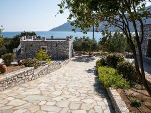a stone walkway in front of a building with a tree at Skoutari Bungalows MELITI room in Skoutari