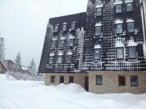 un edificio cubierto de nieve con nieve alrededor en Apartments and rooms Max-Well, en Jahorina