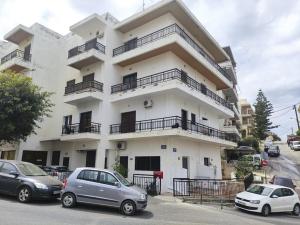 a white building with cars parked in front of it at Amalthia Hotel Apartments in Rethymno