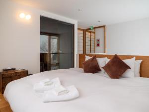 1 dormitorio con 1 cama blanca grande con almohadas marrones en Sekka Ni Chalet, en Niseko
