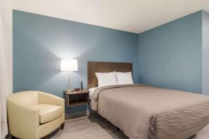 a bedroom with a bed and a chair and a lamp at WoodSpring Suites Jacksonville Baymeadows in Deerwood Club