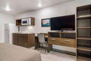 a hotel room with a desk with a television and a bed at WoodSpring Suites Jacksonville Baymeadows in Deerwood Club