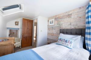 a bedroom with a brick wall and a bed at Niver Dew Holiday Cottage in Lower Boscaswell