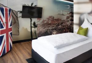 1 dormitorio con 1 cama y TV en la pared en NHI Hotel by WMM Hotels en Neuhaus am Inn