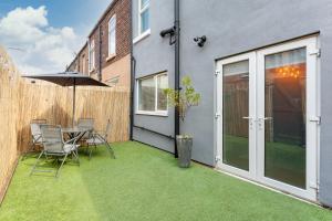 リバプールにあるWatford House - Air Host & Stay - 3 Bedroom Period Houseのテーブルと椅子と傘のあるパティオ