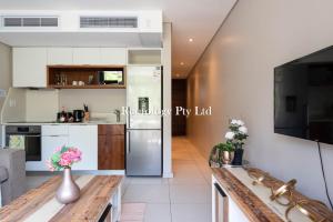 a kitchen with a refrigerator and a table with flowers on it at Lovely 1 Bed Zimbali Suites in Ballito
