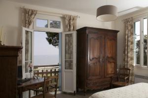 a bedroom with a wooden cabinet and a desk and a window at FLEUR DE SEL in Saint-Trojan-les-Bains