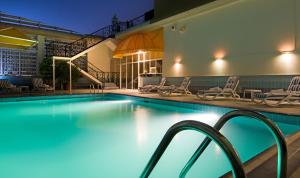 a swimming pool at night with chairs and tables at Copthorne Downtown by Millennium in Abu Dhabi