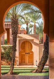 ein Haus mit einer Holztür und zwei Palmen in der Unterkunft Amanjena Resort in Marrakesch