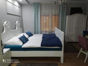 a bedroom with a white bed with blue pillows at Villa Lucia - Apartments&Rooms in Slavonski Brod