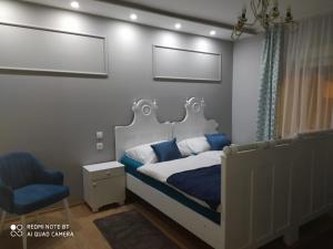 1 dormitorio con 1 cama blanca y 1 silla azul en Villa Lucia - Apartments&Rooms, en Slavonski Brod