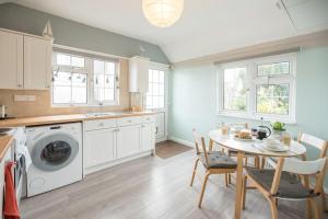 a kitchen with a table and a washing machine at Suncatch Corner, Saxmundham in Saxmundham