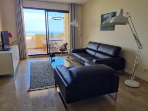 a living room with a black leather couch and a table at Duquesa Village in Manilva