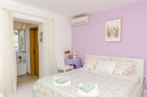 a white bedroom with a white bed and a table at Guest House Ćuk in Dubrovnik