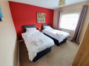 two beds in a room with a red wall at Beverley Central Townhouse Free Parking Sleeps 8 in Beverley