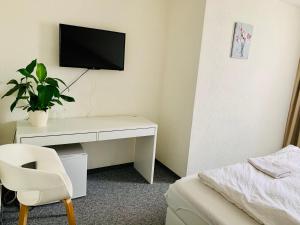 1 dormitorio con escritorio y TV en la pared en Swiss Hotel Krummen Eich Pratteln Free Parking en Pratteln