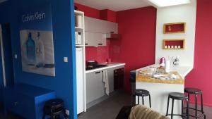 a kitchen with red and blue walls and stools at loft avec parking et terrasse in Chamalières