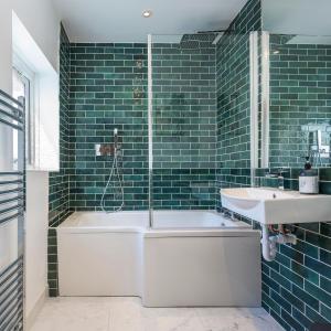 y baño con bañera, lavabo y azulejos verdes. en Stylish Upper Gardner Street - With Free Parking en Brighton & Hove