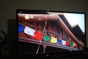 una pantalla de televisión con banderas de oración en una cuerda en Agva Himalaya Motel, en Agva