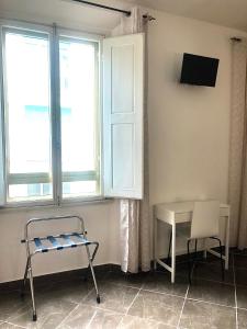 Zimmer mit einem Stuhl, einem Tisch und einem Fenster in der Unterkunft Hotel Nazionale in Florenz