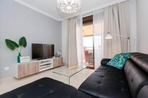 ein Wohnzimmer mit einem schwarzen Sofa und einem TV in der Unterkunft Luxury Apartment Sotavent III in El Médano